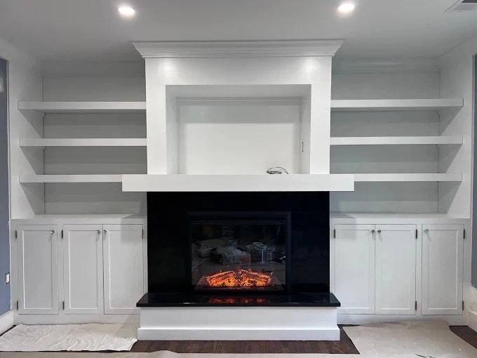White painted built-in with open shelving and lower cabinets on both sides of a fireplace