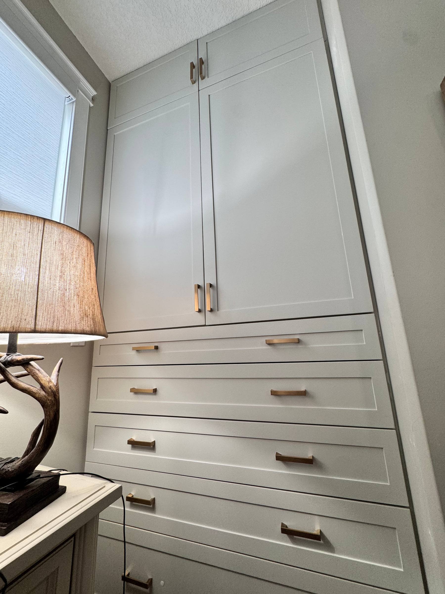 Painted floor-to-ceiling wardrobe with two tall doors over a bank of six drawers with brass pulls