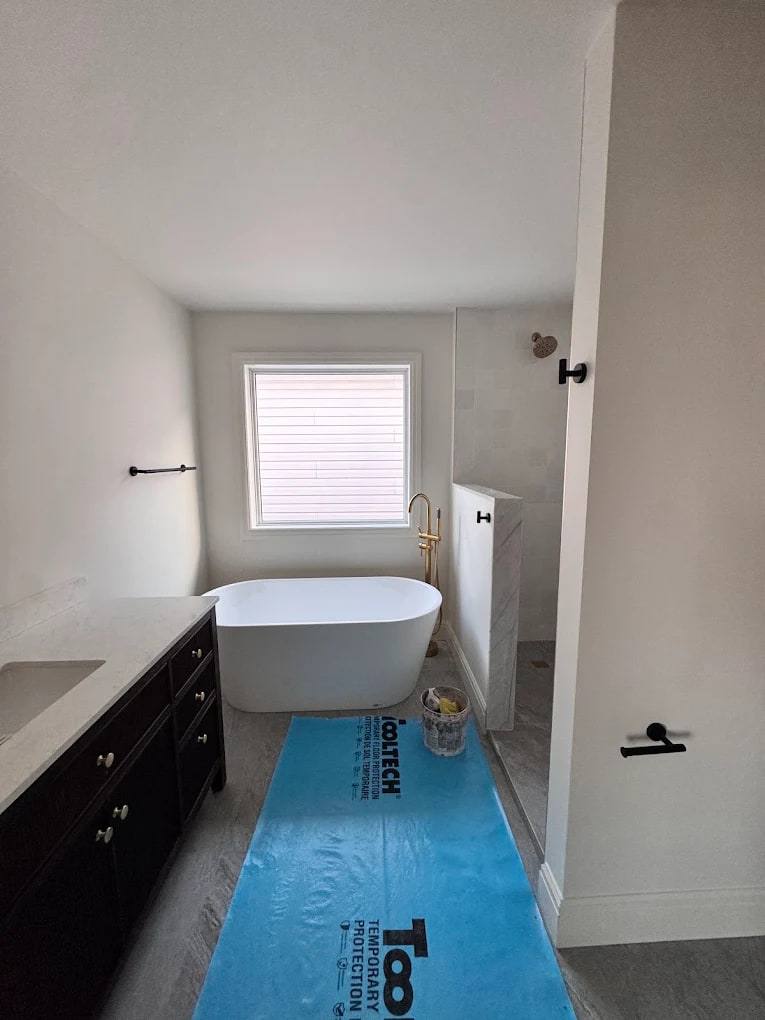 Bathroom with a freestanding tub and dark vanity, newly trimmed with white baseboards and casing