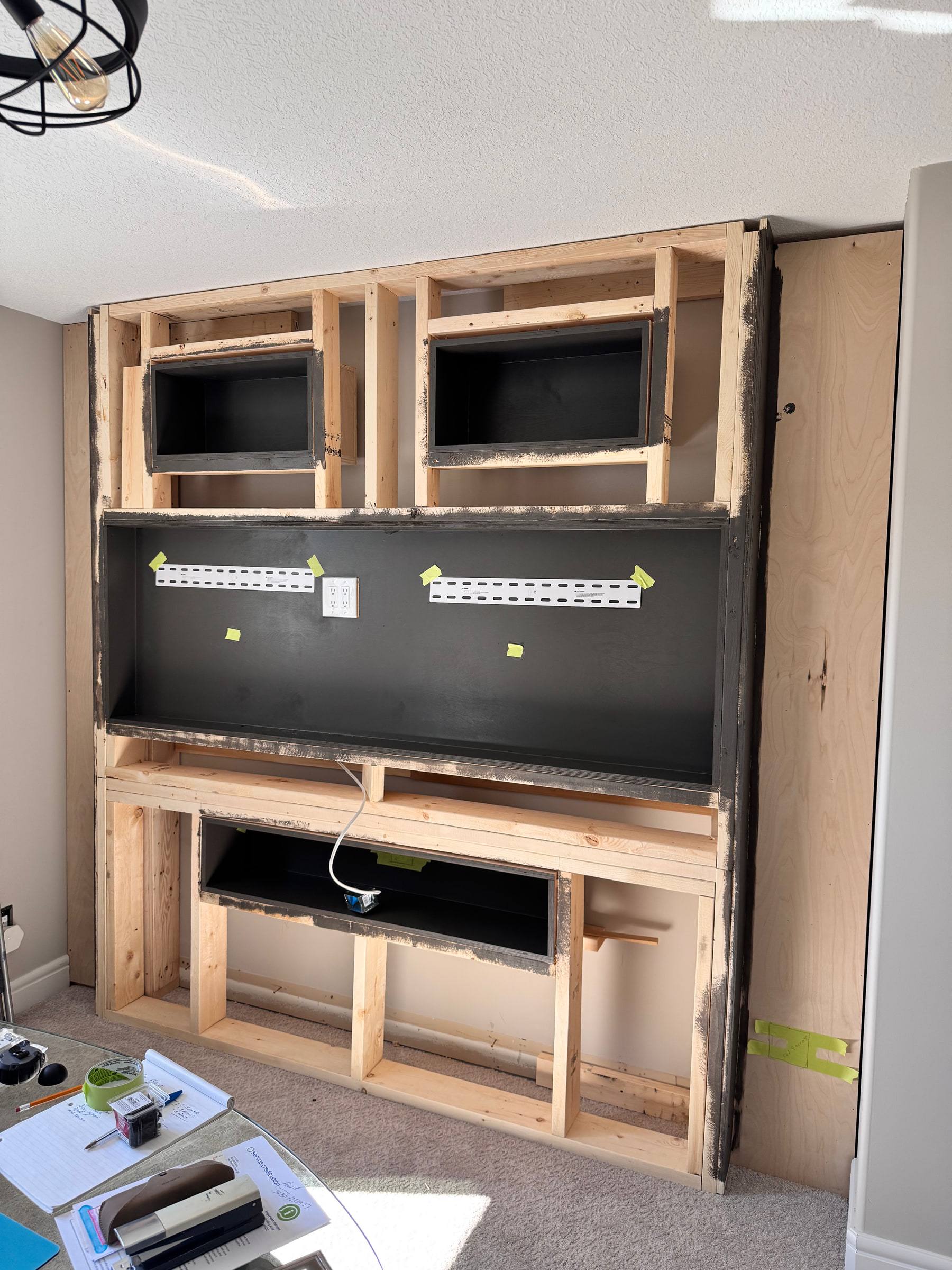Media wall framed in wood with openings for a TV, speakers and a fireplace