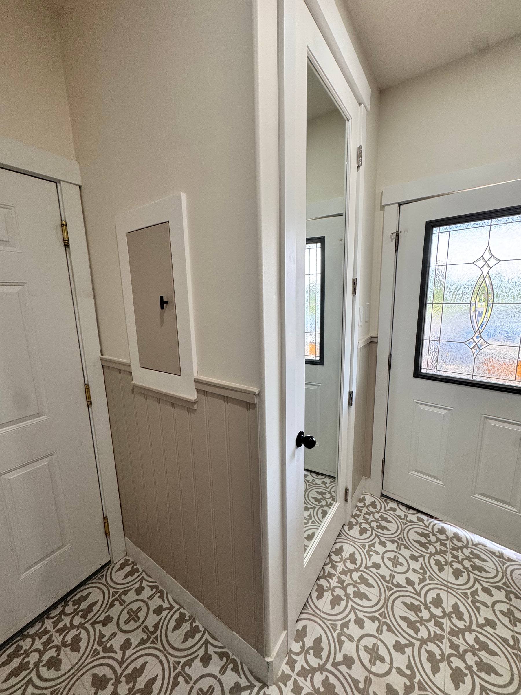 Flush white wall cabinet set into the wall above beadboard wainscoting in the entry