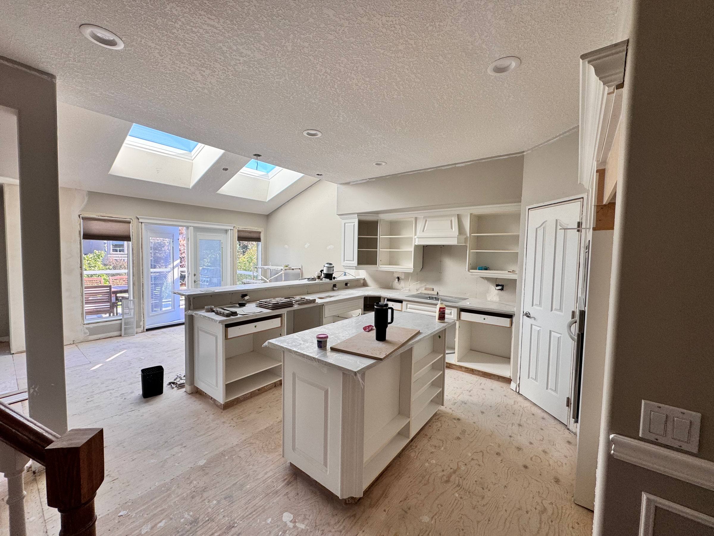 Open kitchen with a new island under skylights during the renovation, subfloor still exposed